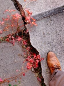 A man walking on cracked concrete sidewalk that needs leveling