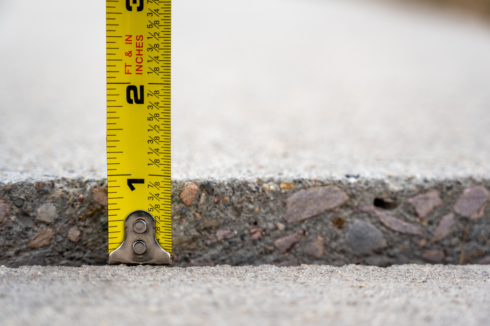 Concrete Damage - image of tape measure measuring the sunken level of concrete.